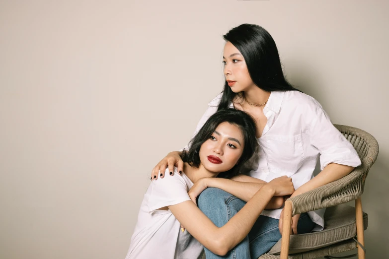 two woman sit in a chair with one sitting on her back