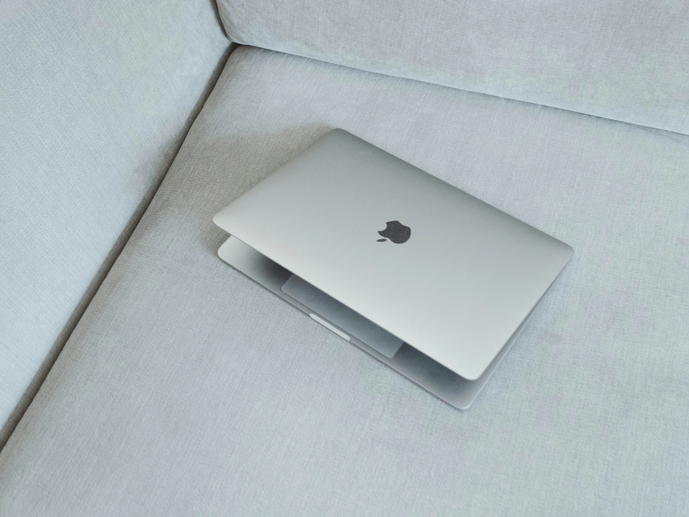 an apple laptop sitting on top of a couch