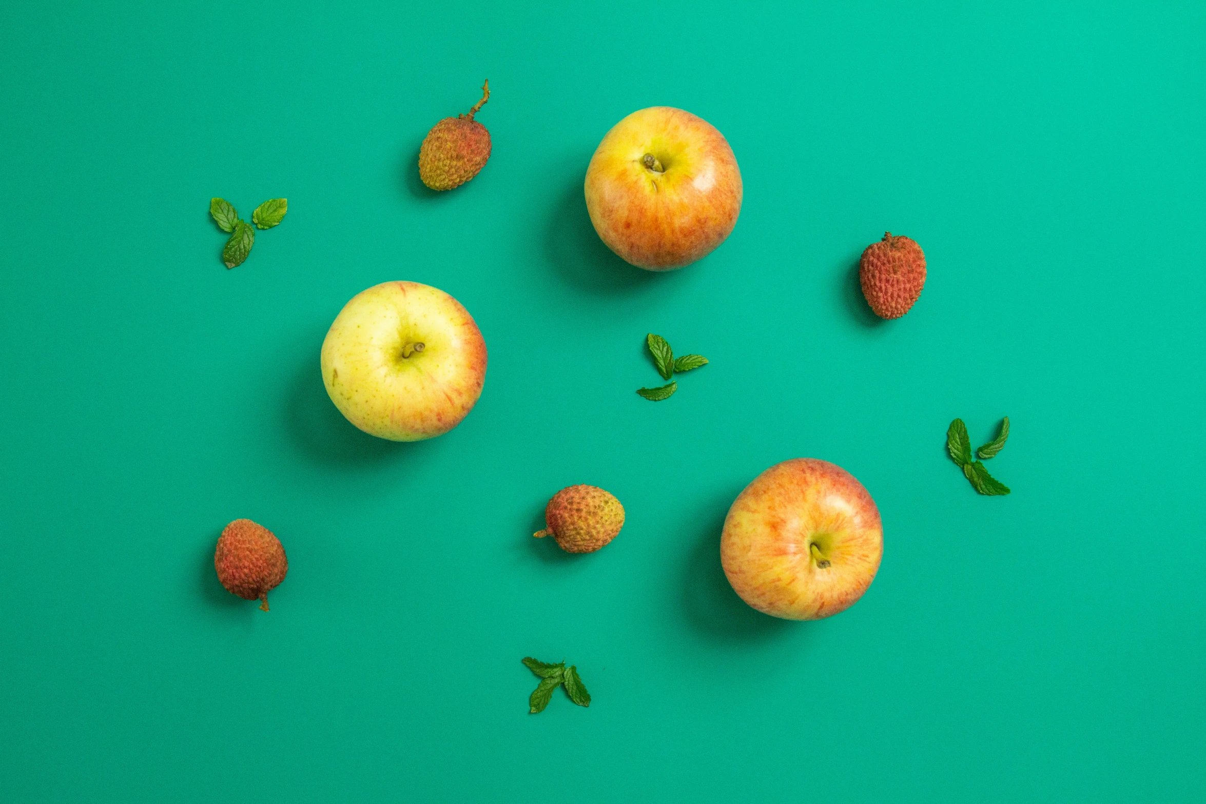 a group of apples and kiwis arranged on a green surface