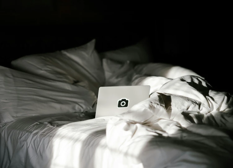 a bed with a white blanket and an open laptop computer