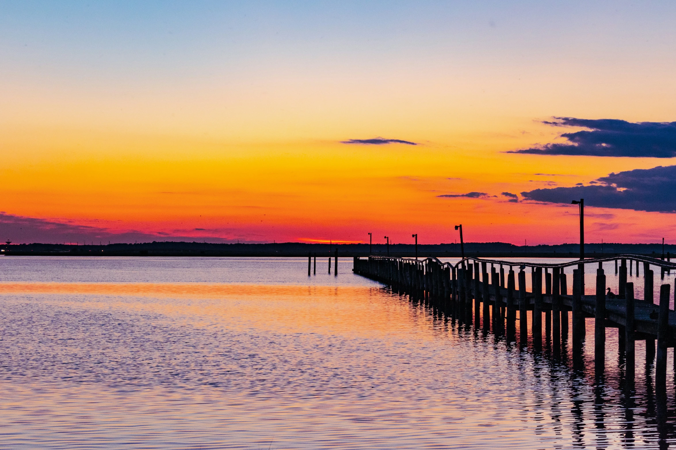 a sunset reflects on the water and some dock