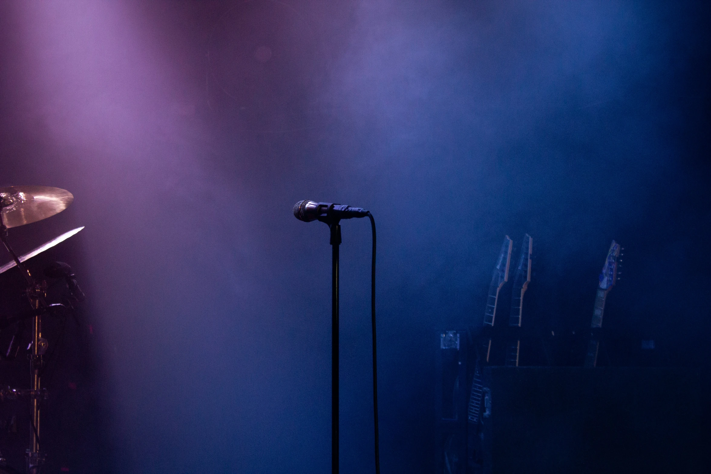 a microphone, microphone, and an open mic stand in front of purple lighting