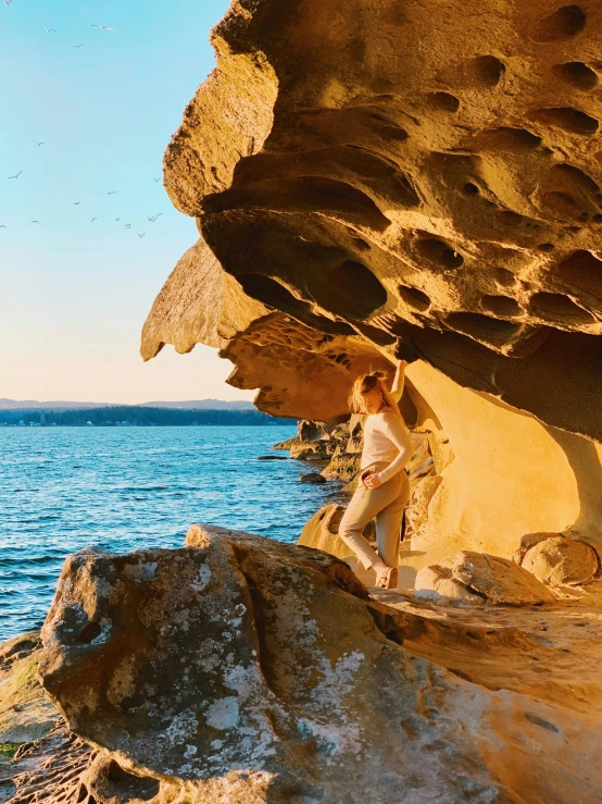 a woman standing on the edge of a rocky cliff near water