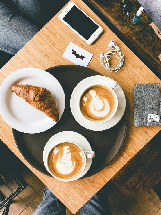 two white plates of coffee sitting next to each other on a wooden table