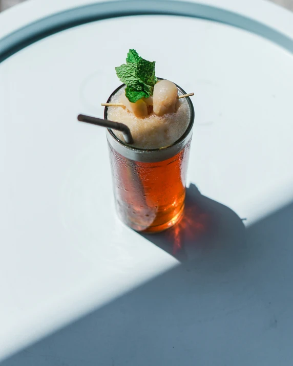 a drink sitting on top of a glass next to a white table