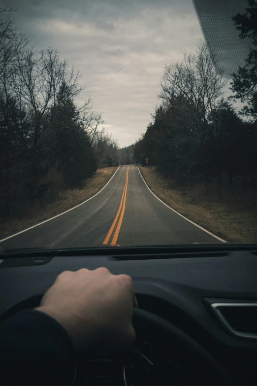 a person is driving along the road with the steering wheel