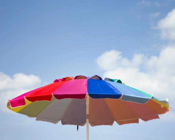 an umbrella over an empty beach with clouds in the background