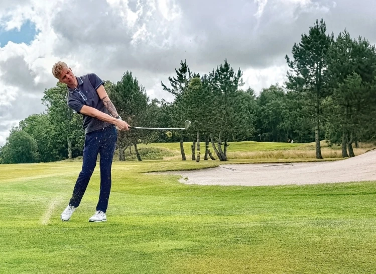 a man holding a golf club hitting a ball