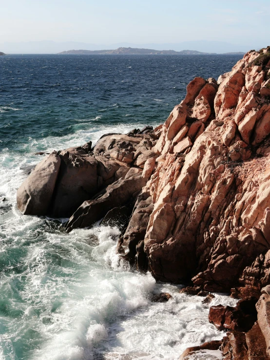 a rocky cliff with blue ocean waters next to it