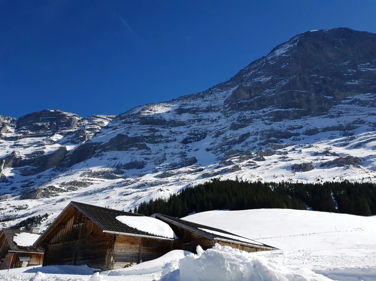 a mountain is covered in snow and a cabin with its roof extended