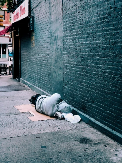 a man laying on the side of a building next to a street
