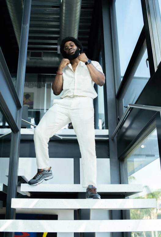 a man in white jumpsuit standing on ledge while talking on his phone