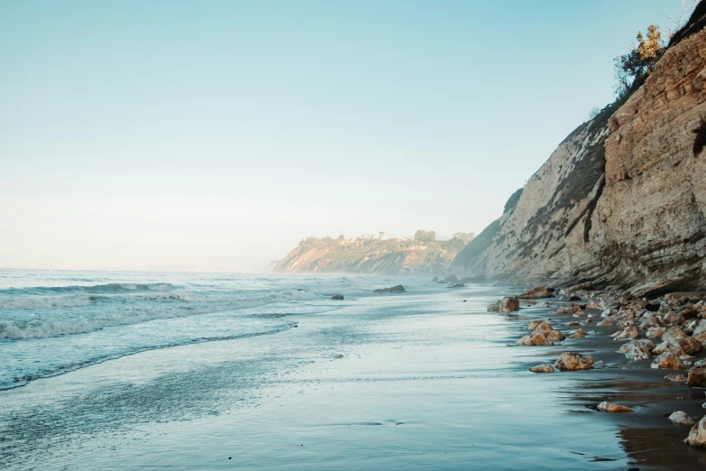 ocean waves roll in toward the shore on a hazy day