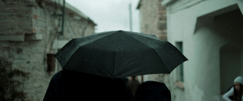 two people walk in the rain holding umbrellas