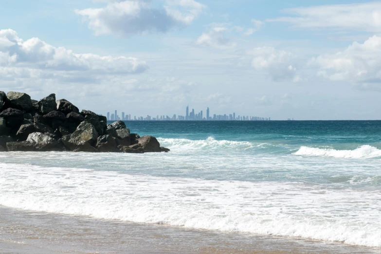 water and rocks on a beach with the city in the background