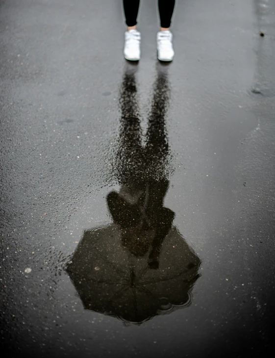 a woman standing in front of a umbrella on the road