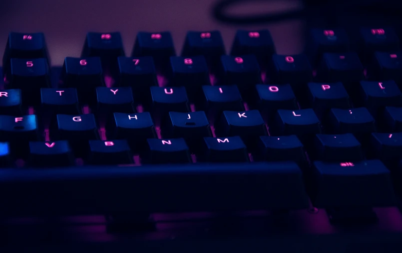 a computer keyboard with blue illuminated keys in a darkened room