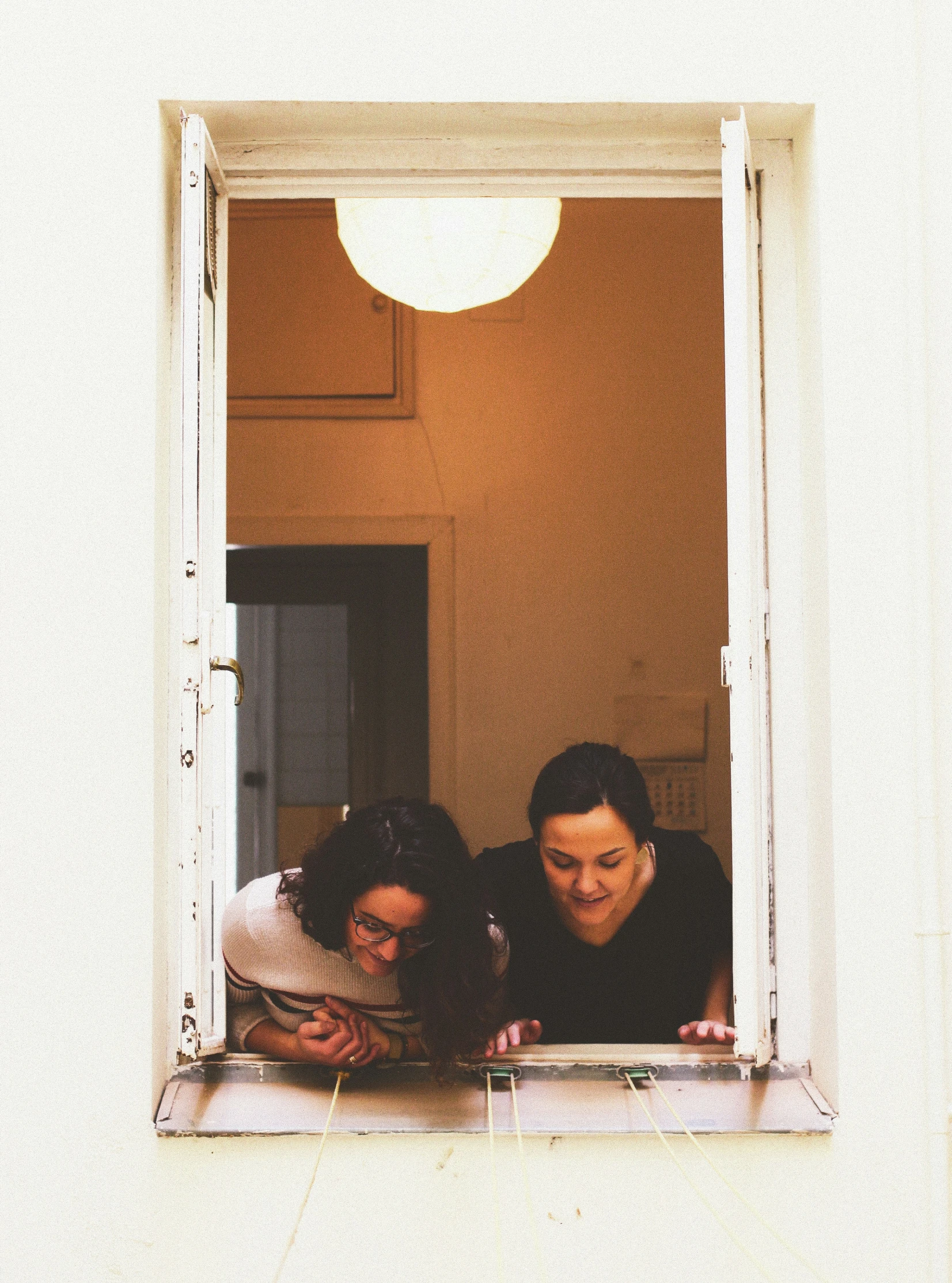 two people look out of the window of a house