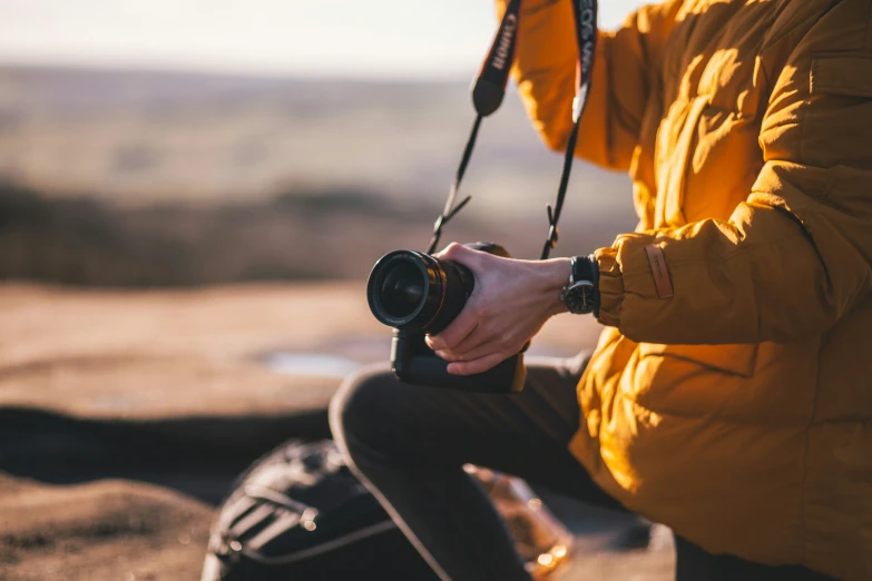 a man wearing an orange jacket holding a camera