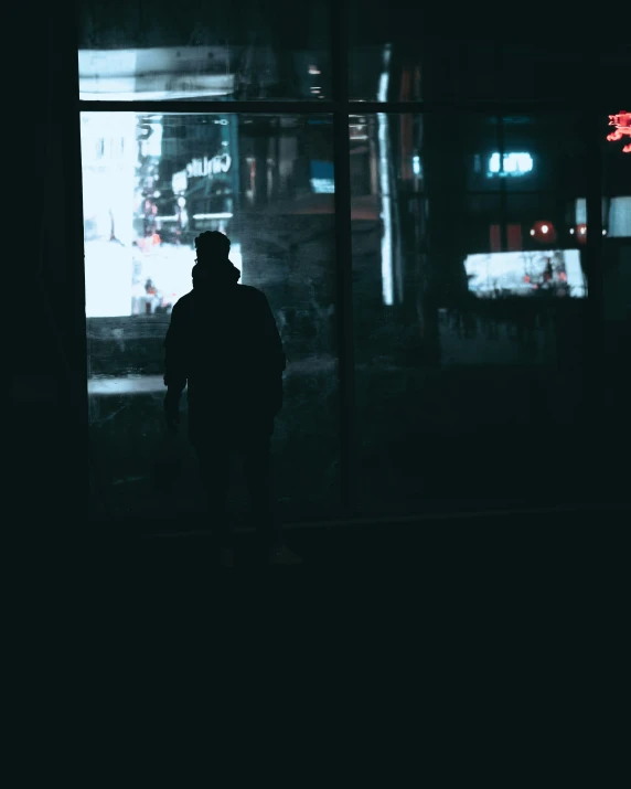 a person is standing near a large window at night