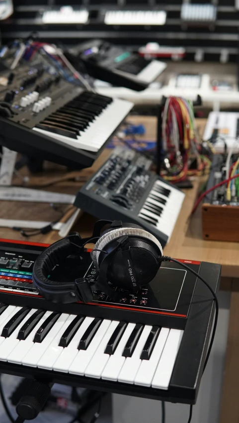 a keyboard and headphones are seen surrounded by other music equipment