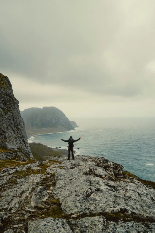 the person is standing on the rocky mountain overlooking the ocean