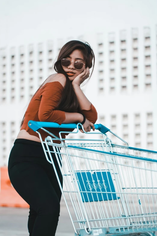 a woman leaning up to her left leaning on a shopping cart