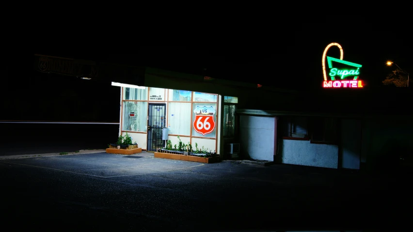 an old motel with an advertising sign lit up at night