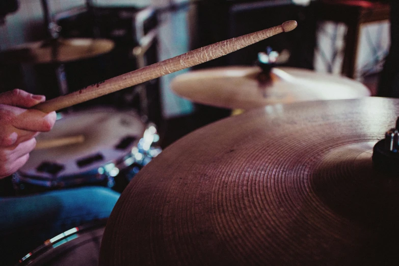 a drummer's hand holding a stick over a drum