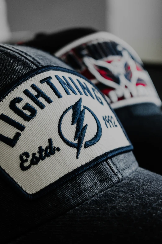 two baseball caps with lightning emblems sitting on top of each other