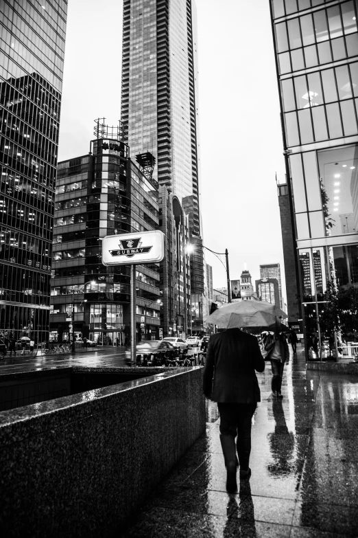 several people walking on a wet sidewalk with umbrellas