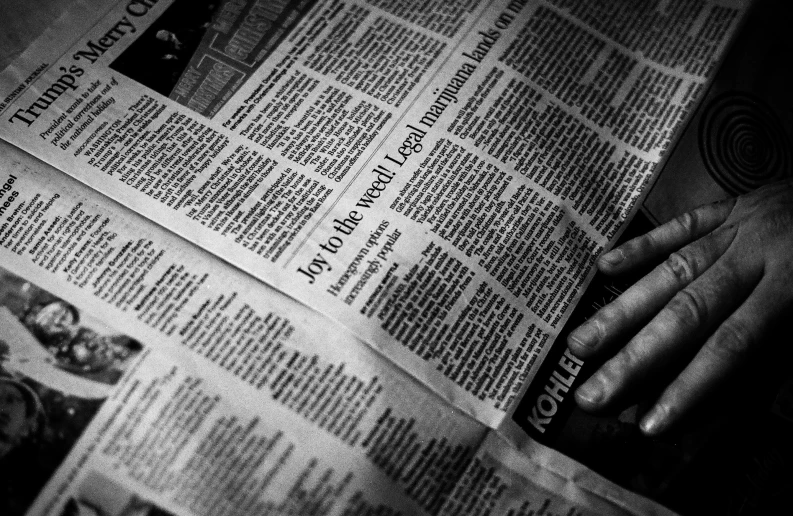 the hands of a person reading the paper with their fingers