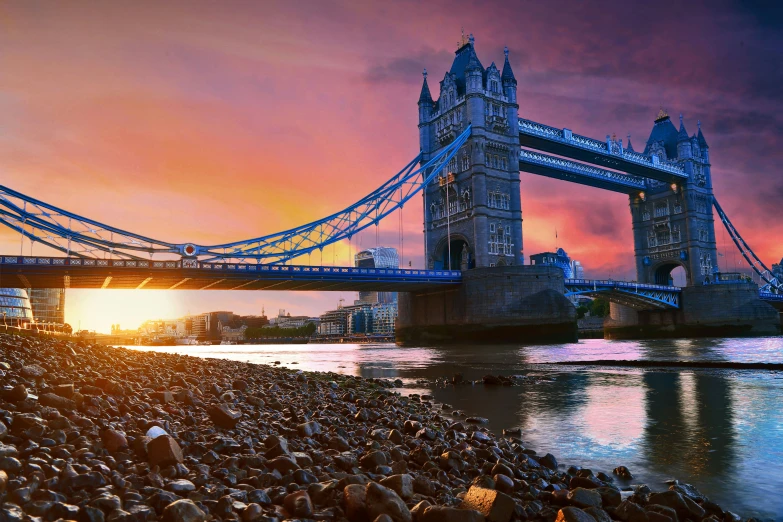 the sun is setting behind the tower bridge