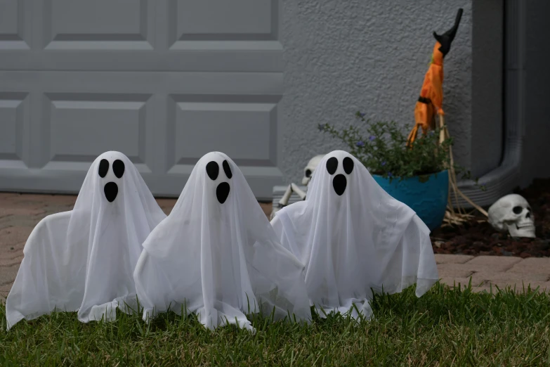 three fake ghost's standing next to each other in grass