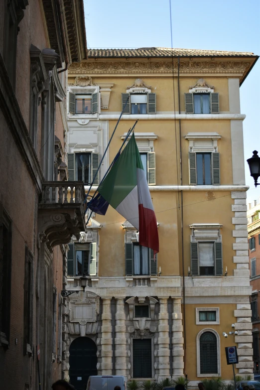 a multi - colored italian flag flying from a building's balcony