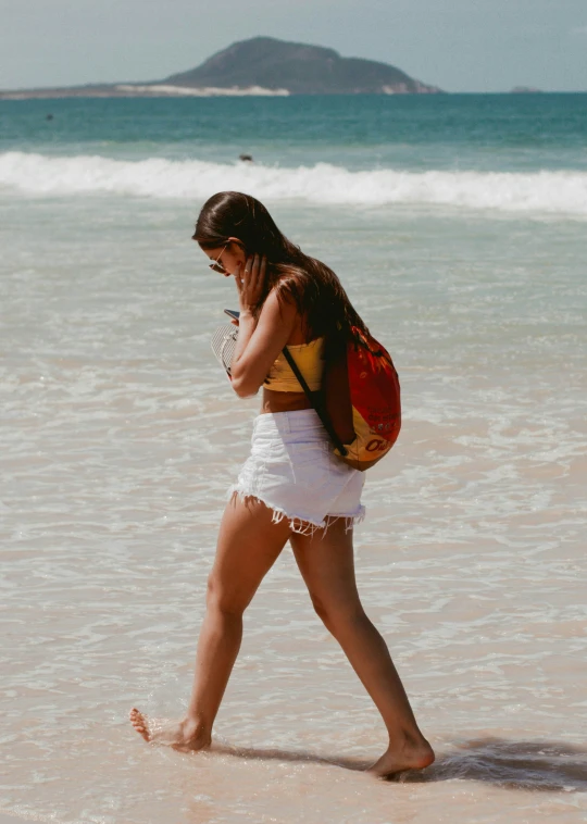 a young woman walking in the sand on the beach