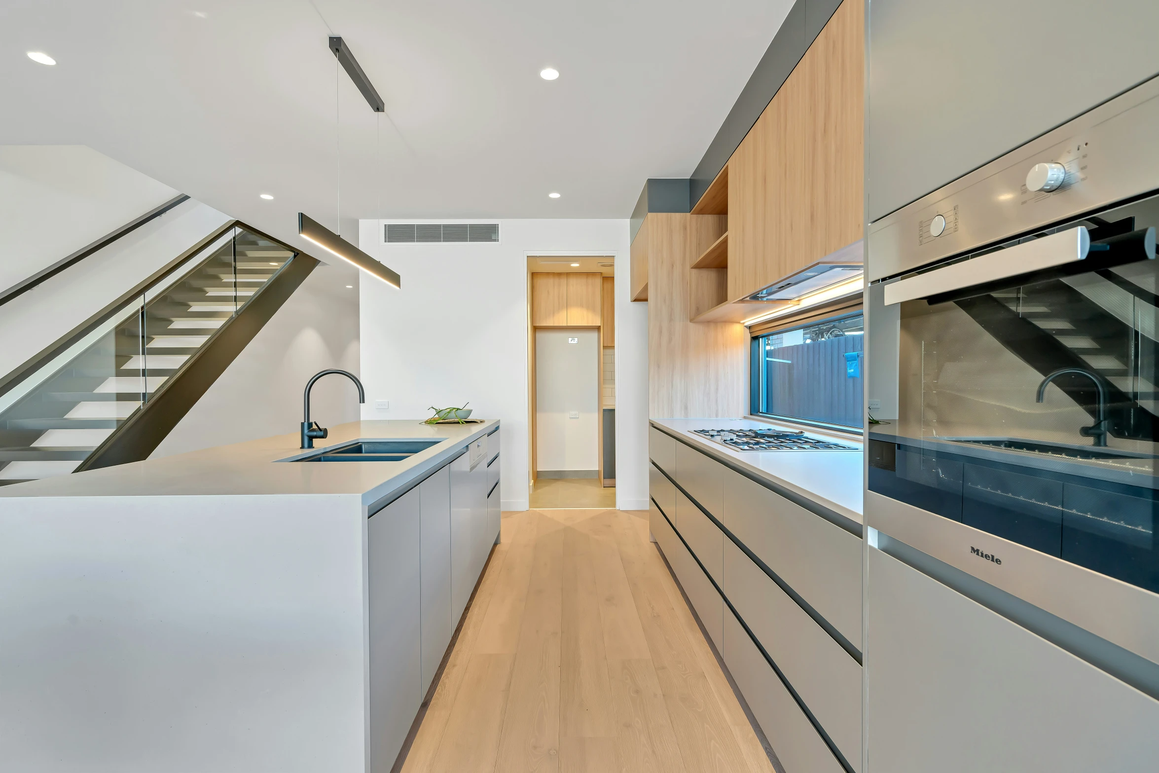 the kitchen has a white counter top and stairs