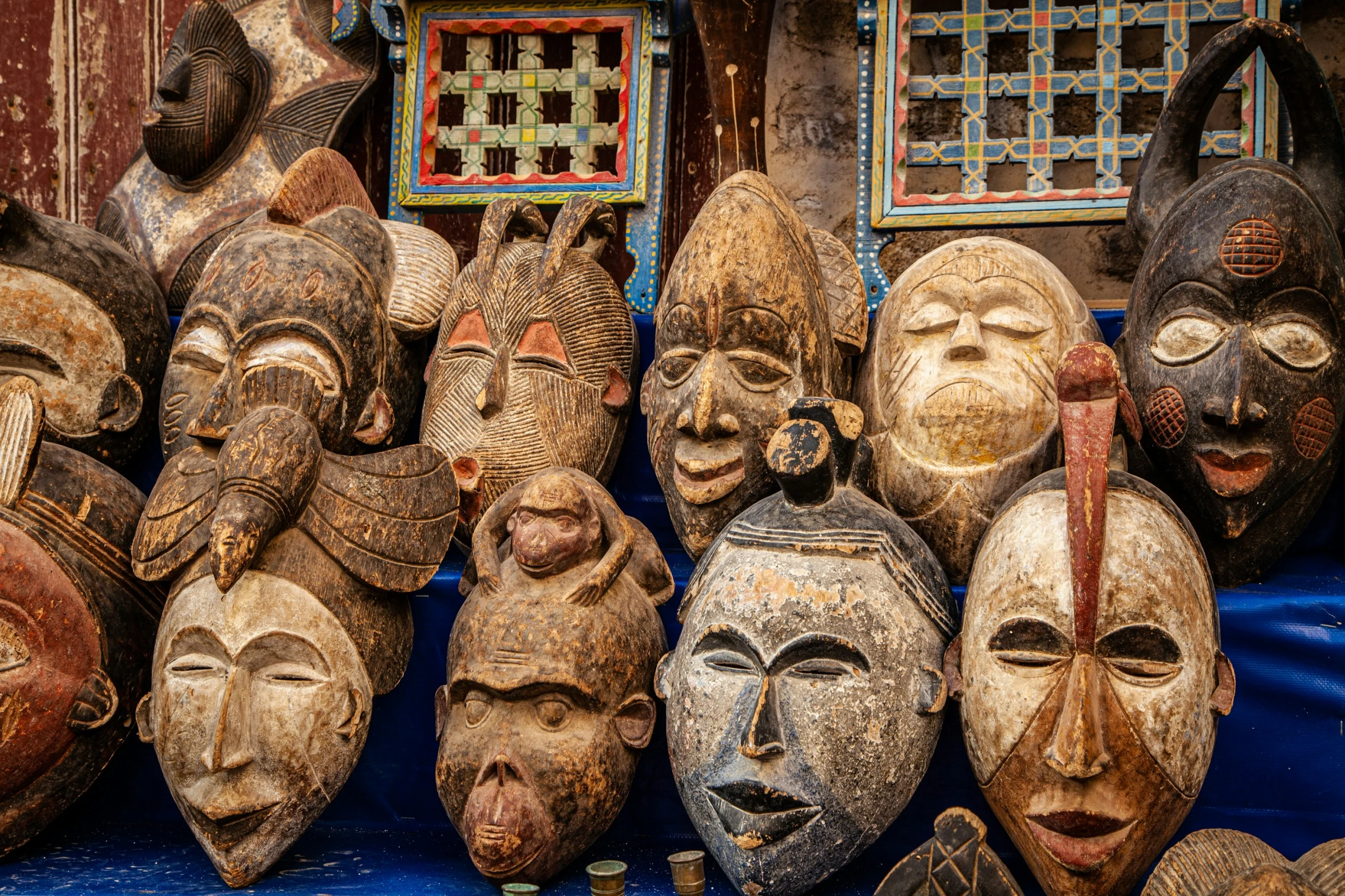 a collection of masks for sale outside a hut