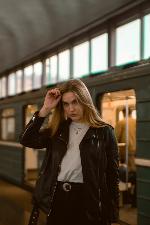 a young blonde woman poses in front of a train