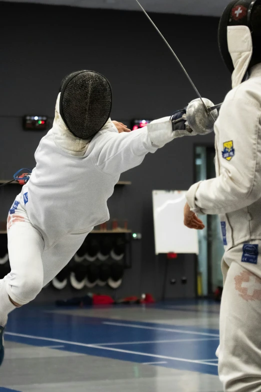 two fencing athletes wearing fencing gear in a room