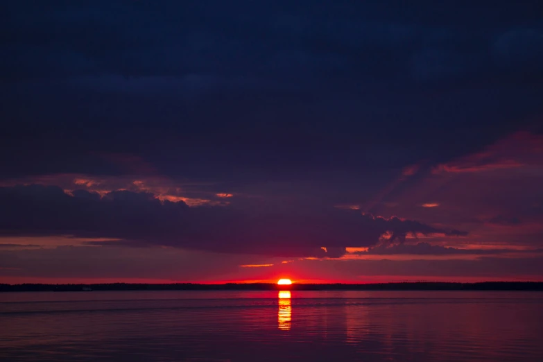 the sun is setting over a lake as seen from the water