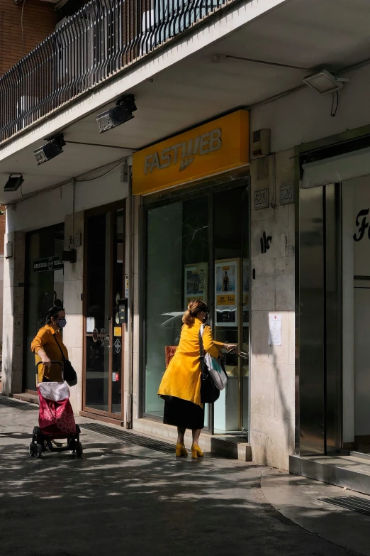 people walk on a street in front of an atm