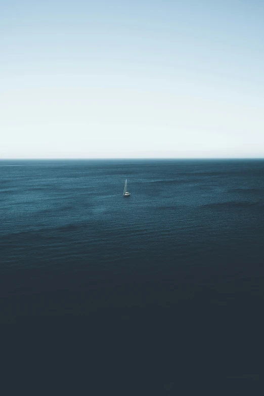 an empty sailboat in open ocean with a bright blue sky