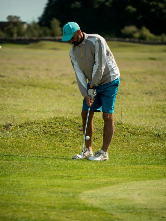 man in blue shorts and tan shirt playing golf