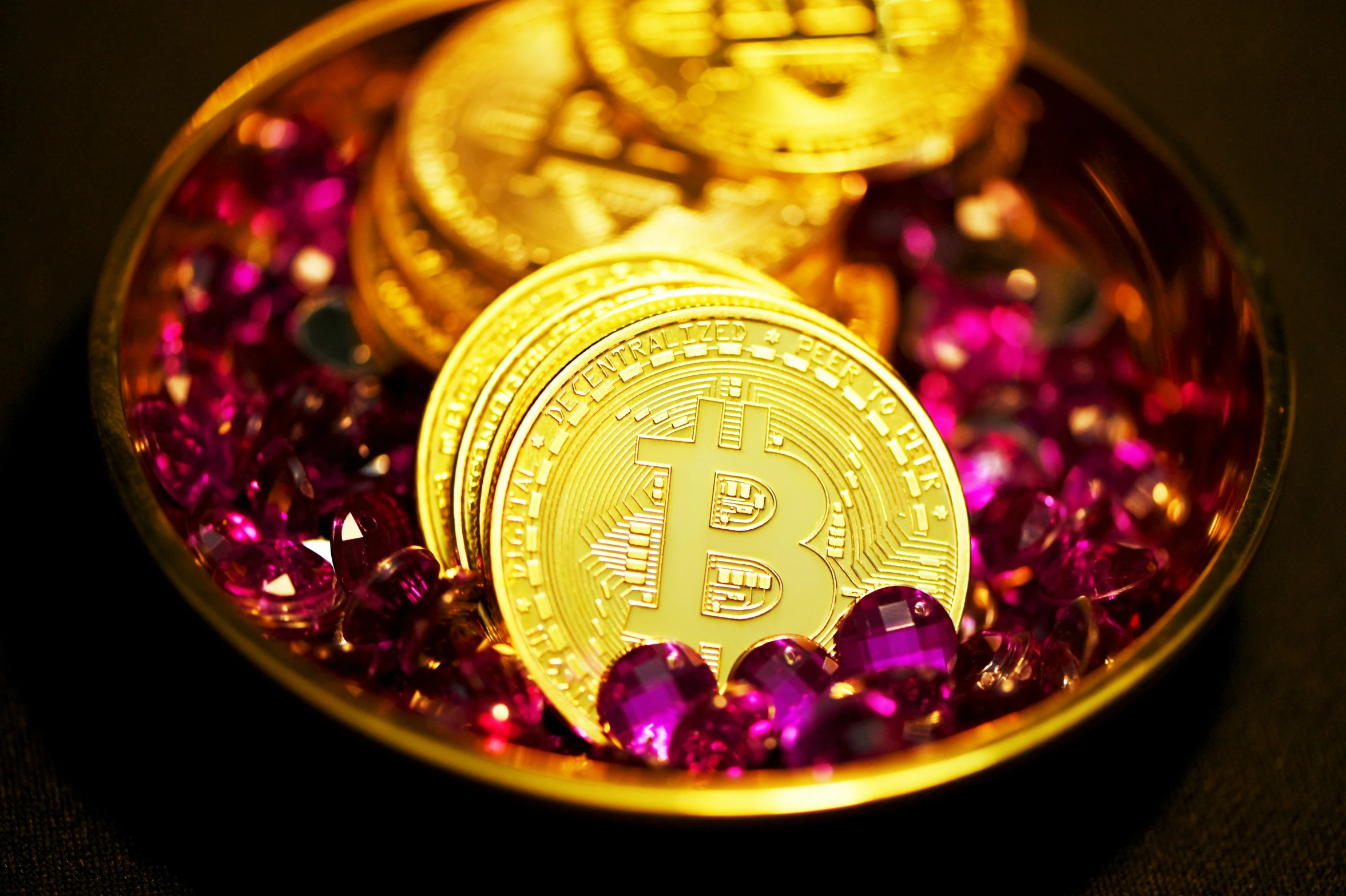 gold bit coin sitting in a pink bowl of other bits