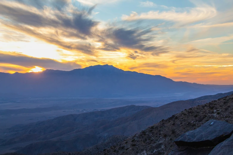 a person standing on the side of a mountain at sunset