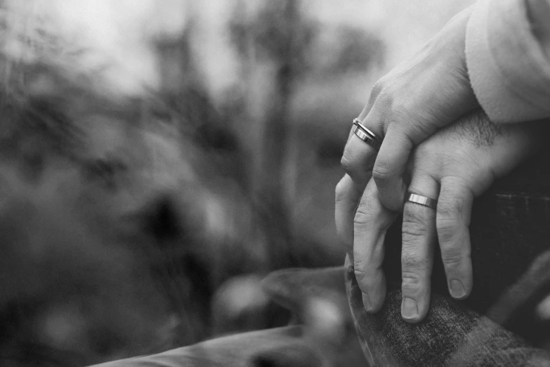 hands with wedding bands holding each other's fingers