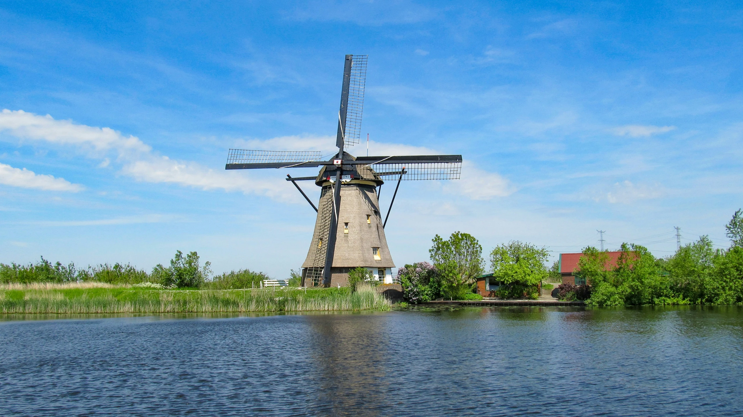 a windmill is seen on the bank of a river