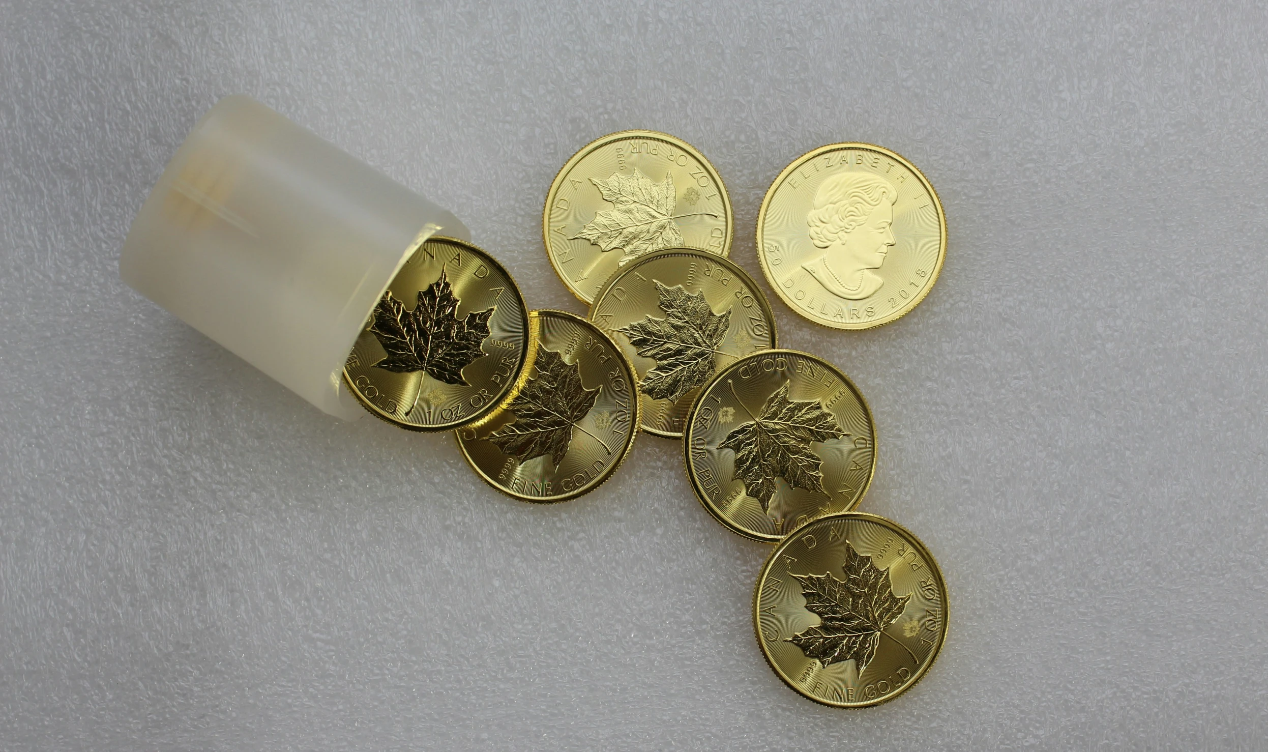 four rolls of money, with different design on them, set against the backdrop