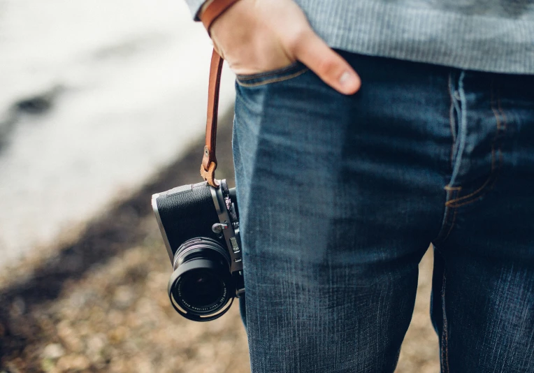 a close up of a person holding a camera and a strap on his waist